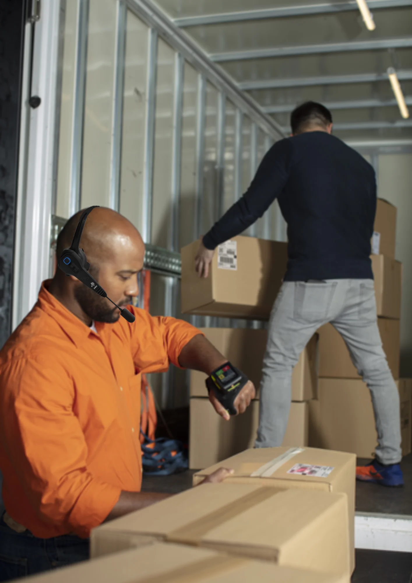 A warehouse operator  equipped with a headset and a wearable hand device is receiving the items.
