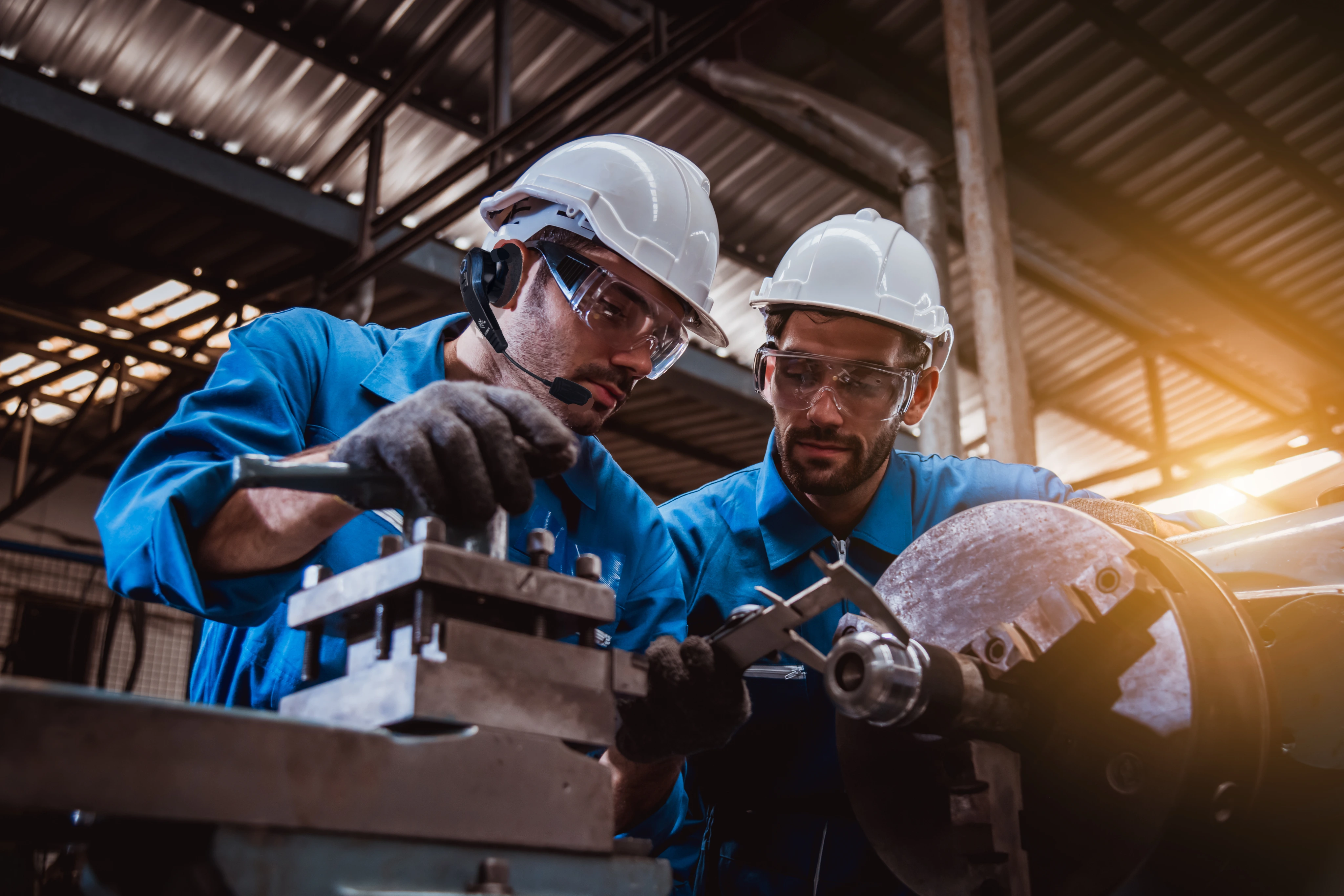 Two operators one equipped with a headset are inspecting a machinery.